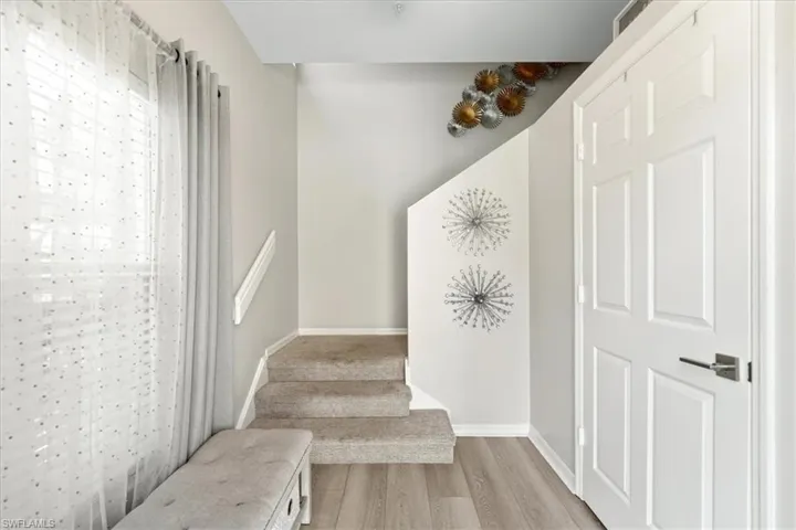 Private interior foyer on first level with LVT flooring, carpeted stairway, leading to second floor split floor plan