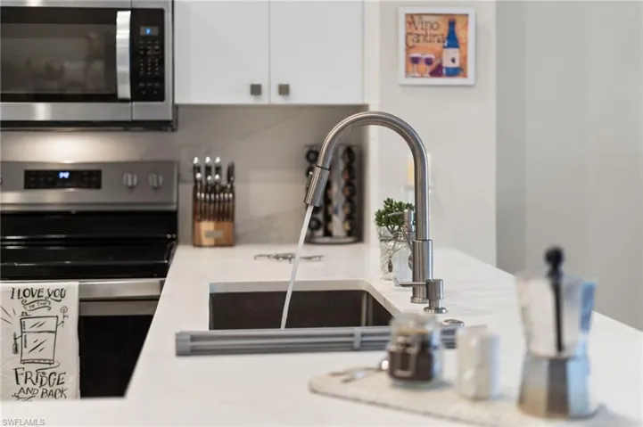 Kitchen with stainless steel appliances, a peninsula, a kitchen bar, vaulted ceiling, LVT floors, quartz countertops