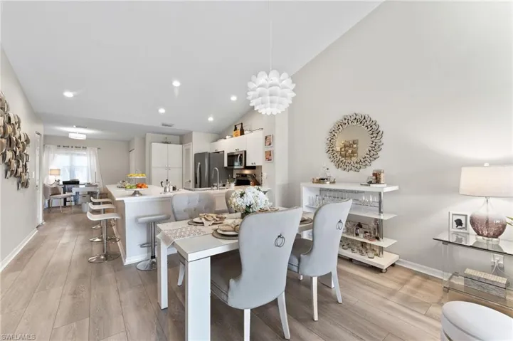 Dining space featuring vaulted ceiling, LVT flooring, recessed lighting, and a chandelier