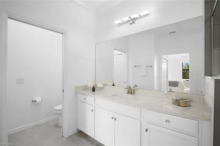 Spacious vanity with light-toned countertop, double white cabinetry, and brushed nickel hardware