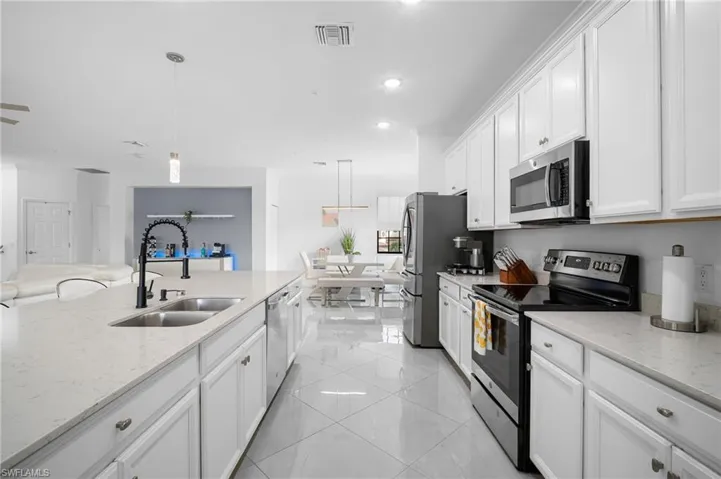 Expansive kitchen island with an undermount double-basin sink and a black gooseneck faucet, set against white cabinetry and light-toned countertops