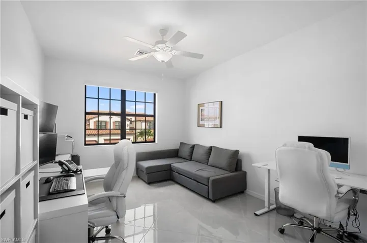Bright room with large grid-paned window, tile flooring, and a ceiling fan with integrated lighting
