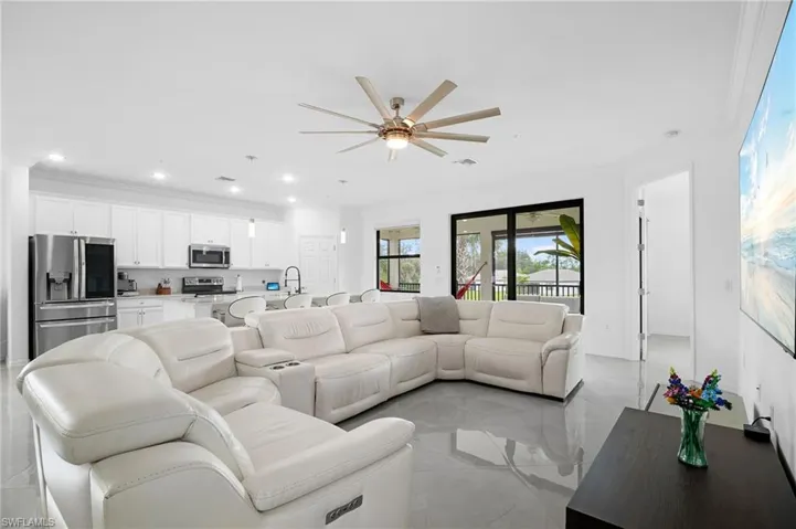 Open-concept living area featuring a modern kitchen, large format tile flooring, recessed lighting, and a ceiling fan