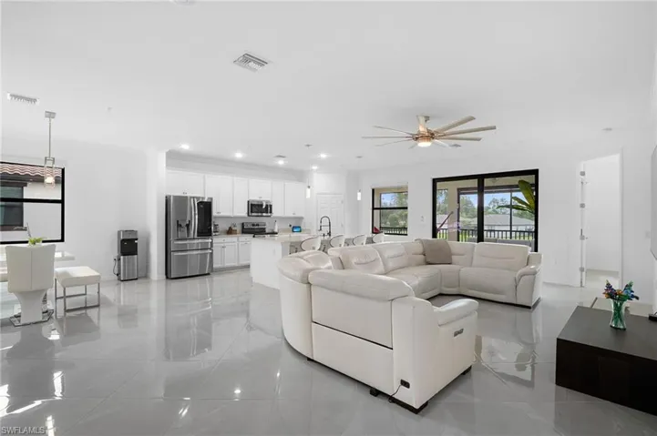 Open-concept living space featuring sleek tile flooring, a modern kitchen with stainless steel appliances and white cabinetry, recessed lighting, and a contemporary ceiling fan
