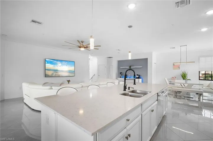 Spacious kitchen island featuring a dual basin sink, black gooseneck faucet, and light-toned countertop