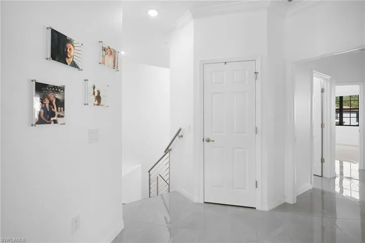 Bright white interior walls with recessed lighting, a six-panel interior door, crown molding, and polished tile flooring