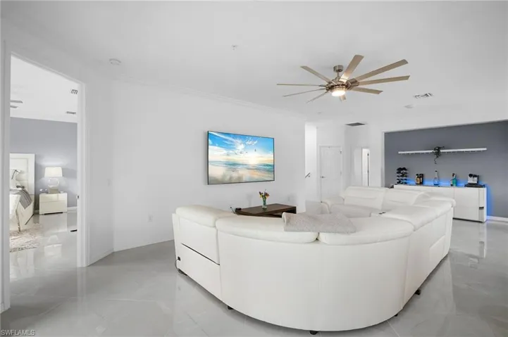 Spacious living area featuring polished tile flooring and crown molding