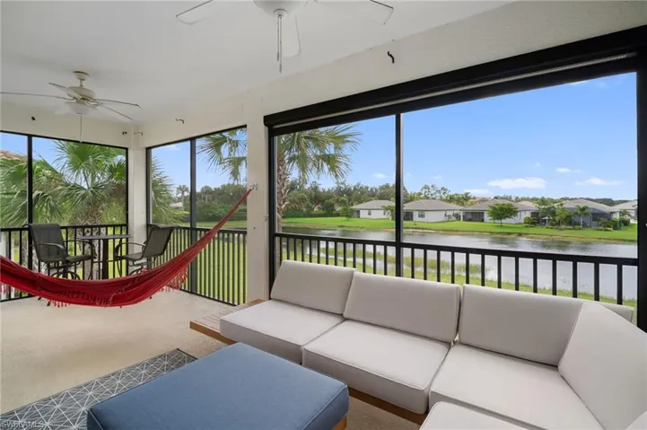 Expansive screened porch featuring a ceiling fan, direct water frontage, and surrounding mature foliage