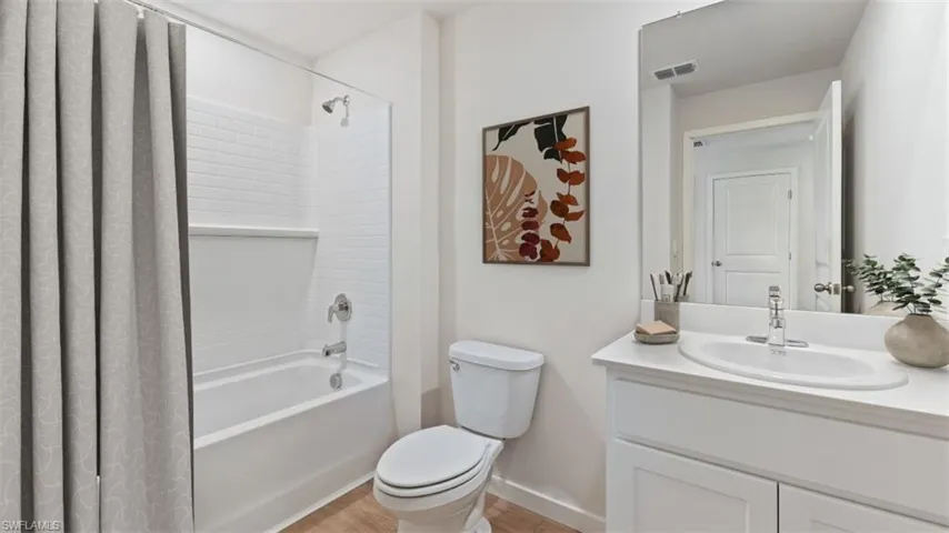 Full bathroom featuring a white vanity with integrated sink, chrome faucet, and storage cabinetry