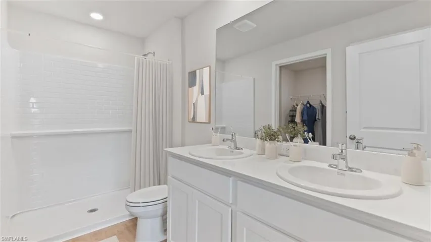 Bathroom featuring a double vanity with white cabinetry, dual undermount sinks, and a large mirror
