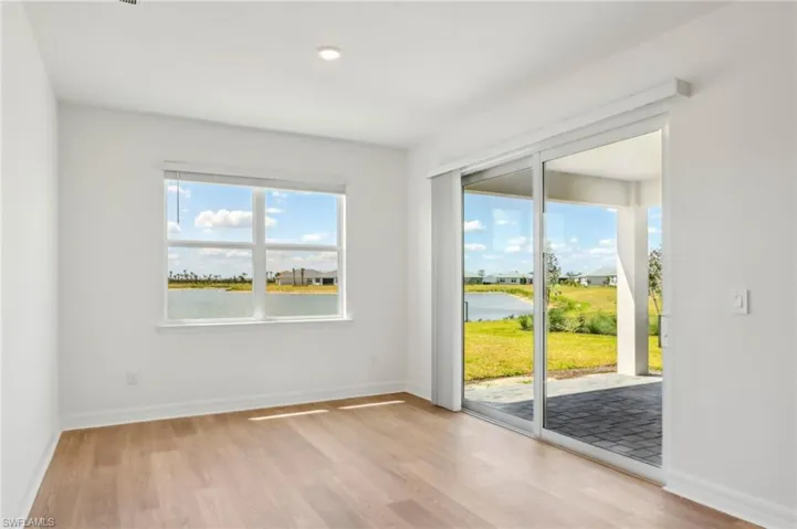 Empty room with light wood finished floors, baseboards, and a water view