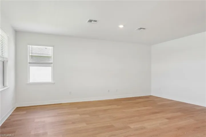 Spare room with light wood-style flooring, baseboards, and visible vents