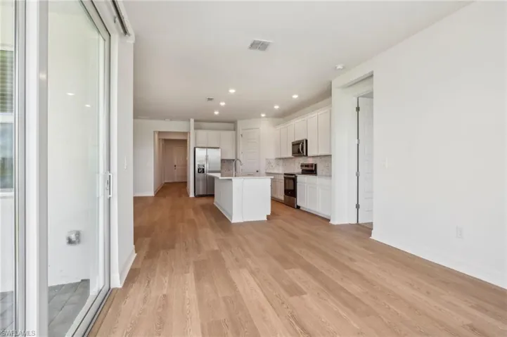 Kitchen with white cabinetry, light wood-style floors, visible vents, decorative backsplash, and appliances with stainless steel finishes