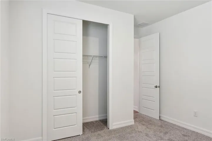 Unfurnished bedroom with a closet, baseboards, carpet flooring, and visible vents