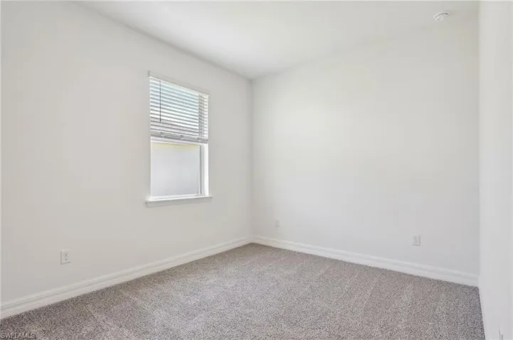 Carpeted spare room featuring baseboards