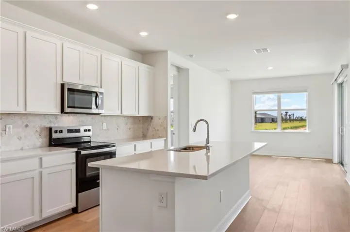 Kitchen featuring an island with sink, visible vents, appliances with stainless steel finishes, a sink, and backsplash