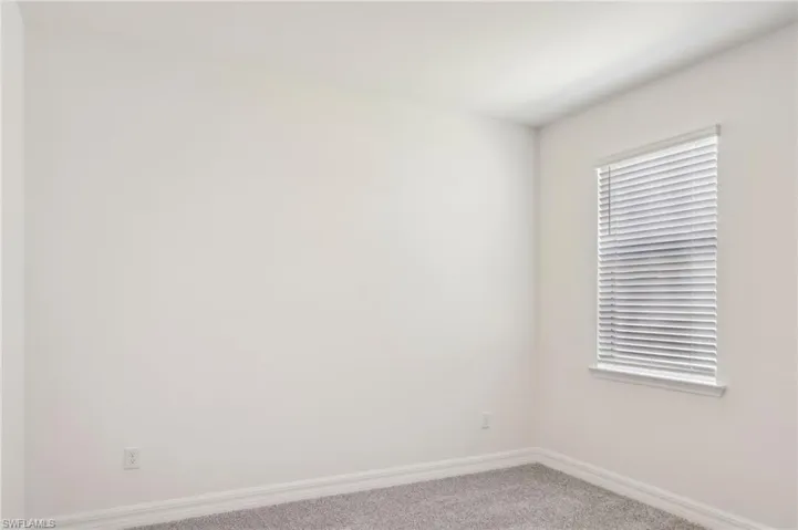 Carpeted spare room featuring baseboards
