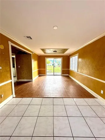 Interior room featuring a tray ceiling with recessed lighting, wood-finish flooring, and white baseboards