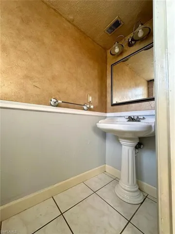Pedestal sink with chrome fixtures, framed mirror, and two-light vanity fixture