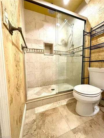 Spacious shower enclosure with glass sliding doors, featuring a built-in shower niche and a decorative tile accent band