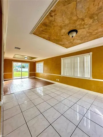 Expansive interior space featuring a recessed ceiling with decorative finish, white ceramic tile flooring, and wood-finish flooring