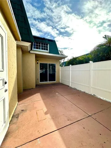 Private outdoor patio space featuring concrete surfacing and a white privacy fence