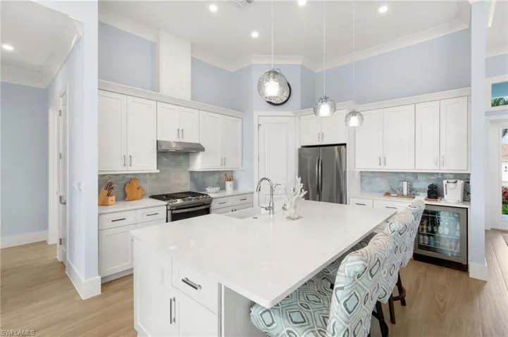 Kitchen featuring wine cooler, white cabinets, stainless steel appliances, white quartz counters and island