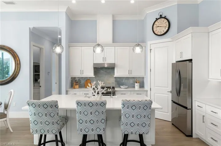 Kitchen with large bar/seating area, SS appliances, white cabinets and white quartz counters
