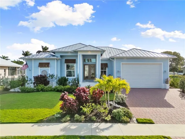 View of front of home featuring a garage, a standing seam roof, decorative driveway, and a front lawn