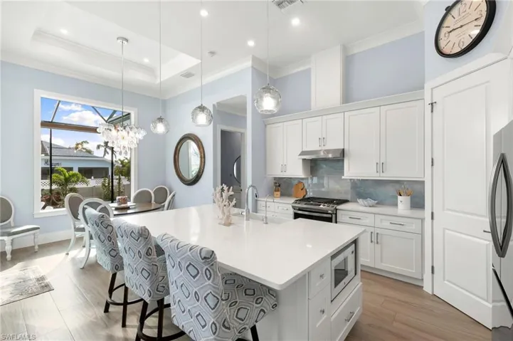 Kitchen with white cabinets, SS appliances with stainless steel finishes, light countertops, pendant lighting