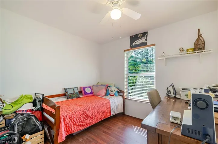 Bedroom with an office area, wood finished floors, and a ceiling fan