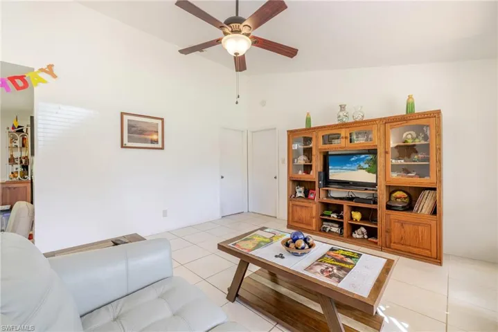 Living area featuring light tile patterned flooring, a ceiling fan, and high vaulted ceiling