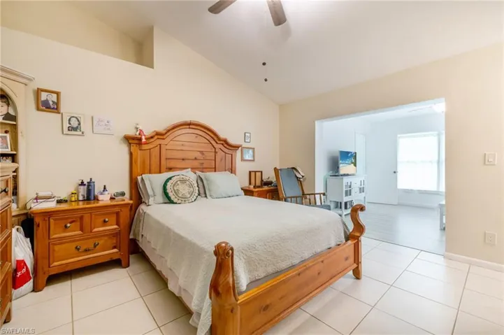 Bedroom with vaulted ceiling, light tile patterned flooring, and a ceiling fan