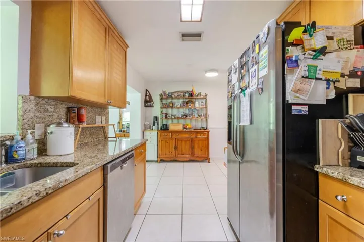 Kitchen with decorative backsplash, light stone countertops, appliances with stainless steel finishes, and light tile patterned floors