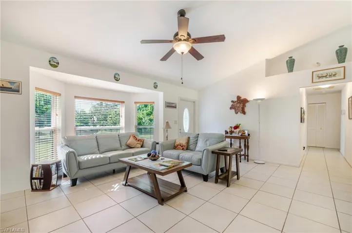 Living area featuring lofted ceiling, light tile patterned floors, and a ceiling fan