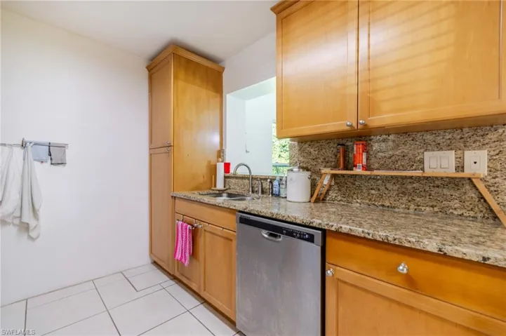 Kitchen featuring decorative backsplash, dishwasher, light tile patterned flooring, and light stone countertops