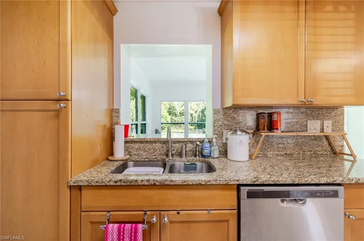 Kitchen featuring light stone countertops, stainless steel dishwasher, and tasteful backsplash