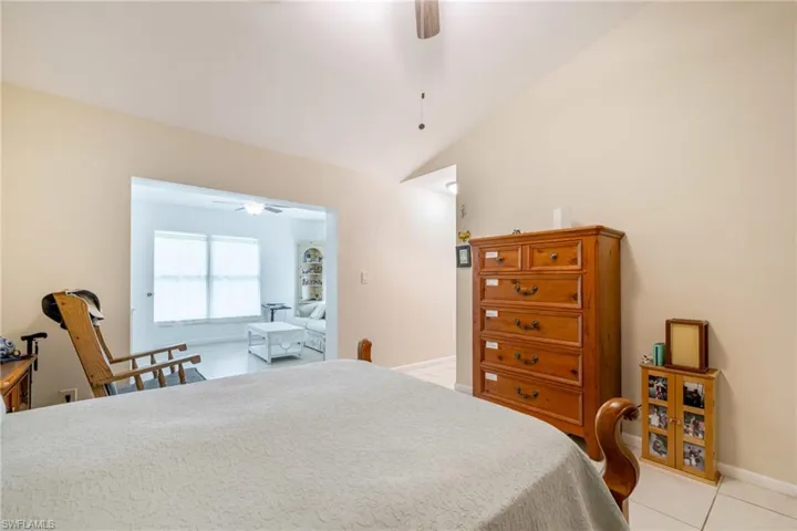 Bedroom featuring a ceiling fan, lofted ceiling, and light tile patterned flooring