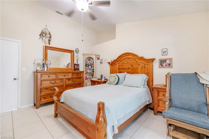 Bedroom with light tile patterned floors, ceiling fan, and vaulted ceiling