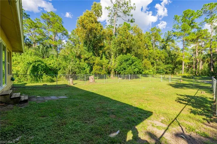 Fenced backyard with view of wooded area