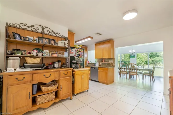Kitchen with open shelves, light tile patterned floors, backsplash, a chandelier, and dishwasher