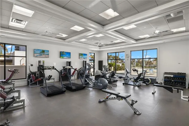 Exercise room featuring a ceiling fan, coffered ceiling, a paneled ceiling, and beamed ceiling