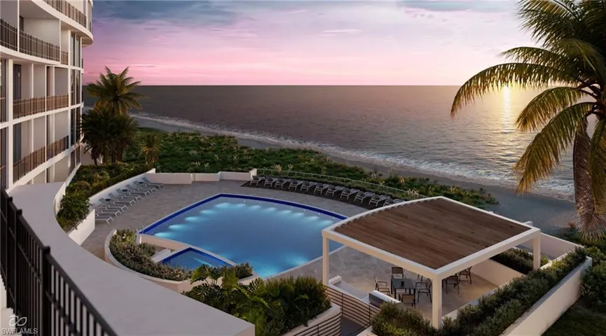 View of pool with a patio, view of water and beach, and a pool with connected hot tub