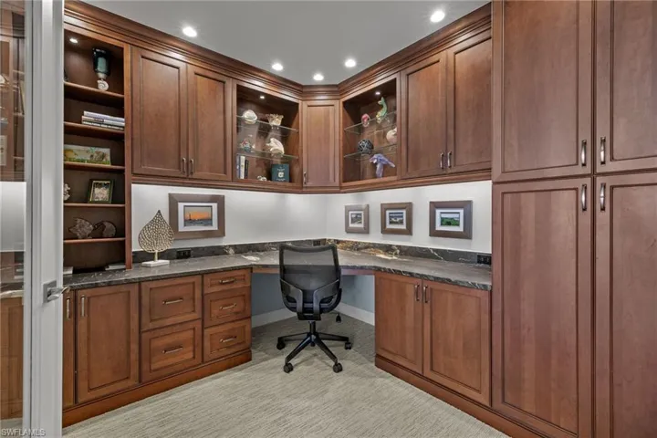 Office space with built in desk, recessed lighting, and light carpet