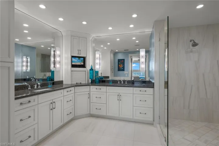 Full bathroom featuring a stall shower, recessed lighting, two vanities, and light tile patterned floors
