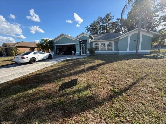Ranch-style home featuring stucco siding, driveway, a front lawn, and an attached garage