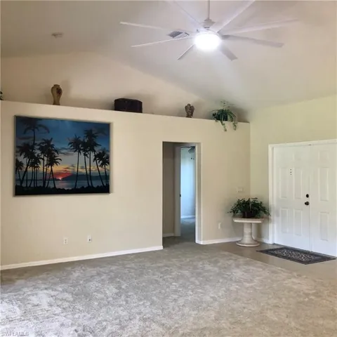 Living room featuring vaulted ceiling & large ceiling fan