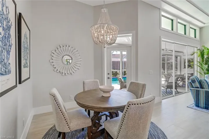 Dining room with a high ceiling, plenty of natural light, a chandelier, and light wood-style flooring