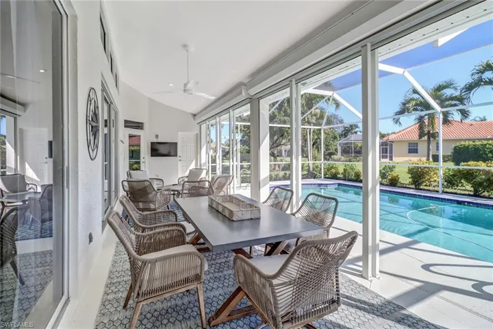 Sunroom with healthy amount of natural light, a swimming pool, and vaulted ceiling