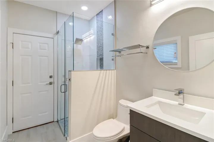 Bathroom with vanity, a shower stall, and light wood-style flooring